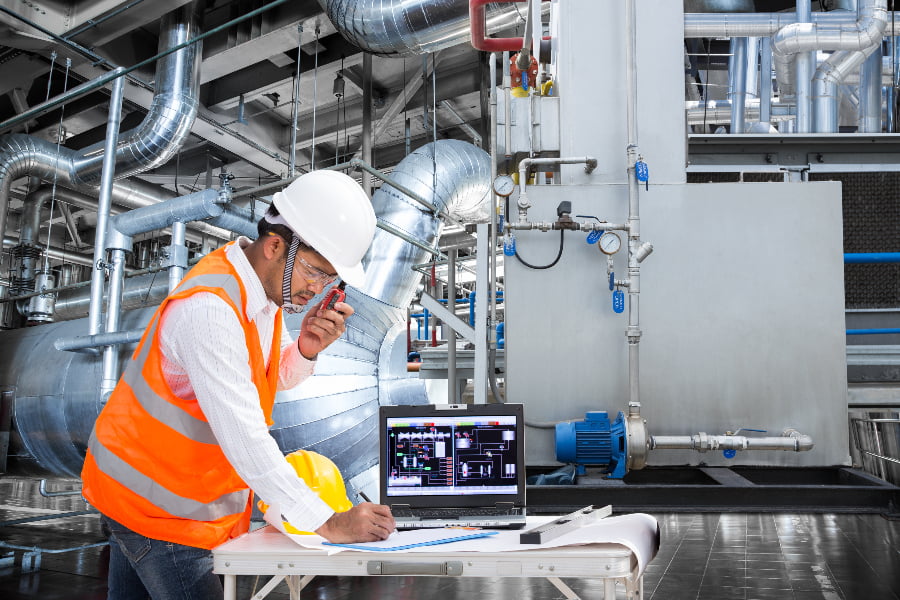 Controls engineer in plant with laptop showing SCADA
